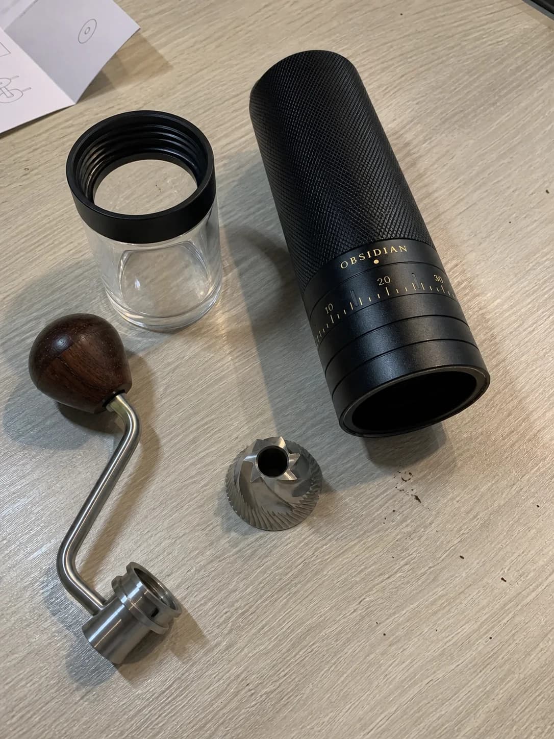 Simulated amateur phone photograph of the fictional Obsidian grinder taken apart on a table