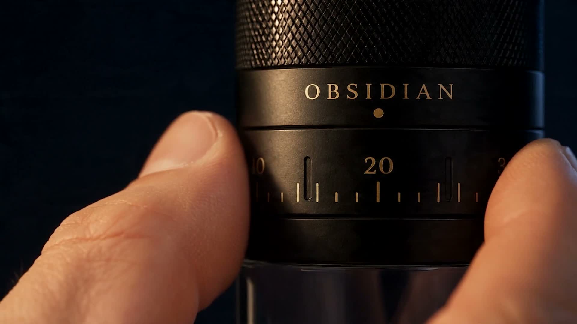 Attention beat: a hand sets the fictional grinder's numbered dial